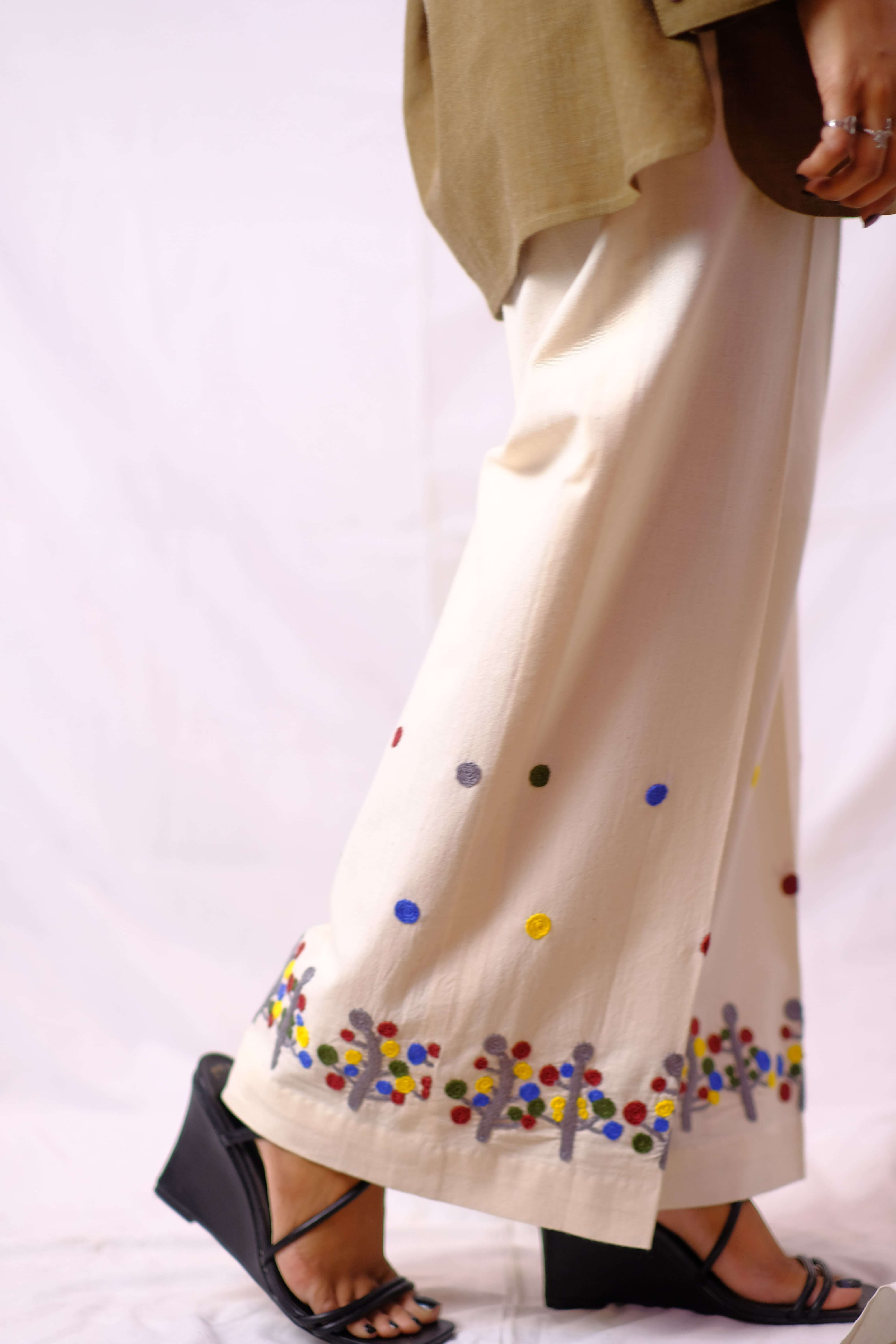Elegant off-white wide-leg trousers with vibrant hand-embroidered floral detailing for a touch of artistry and charm.